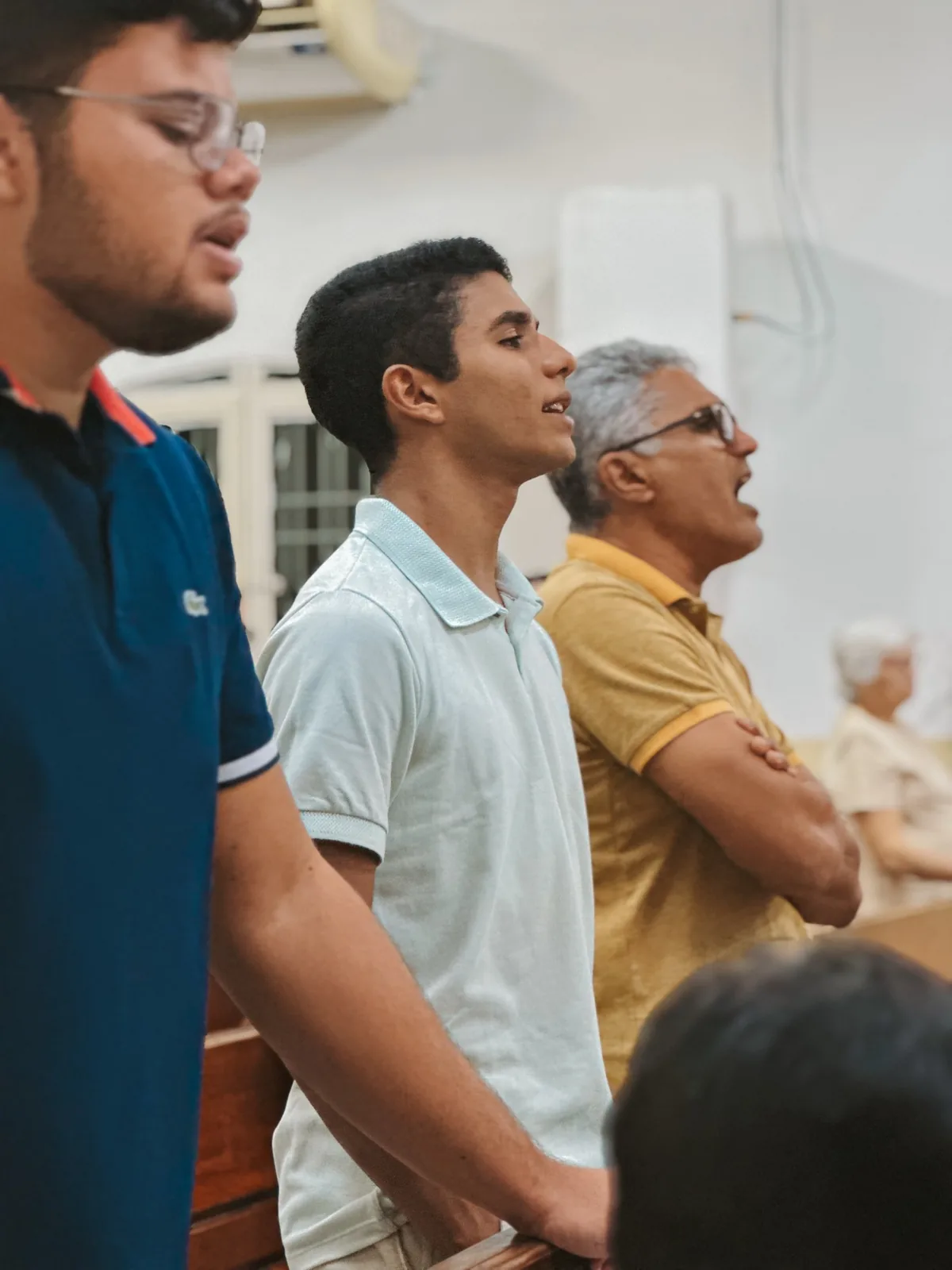Membros da igreja, de pé, cantando durante o culto